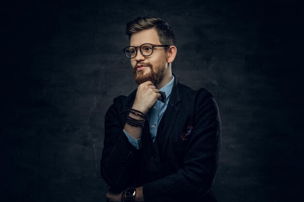 Guapo hombre elegante barbudo en anteojos vestido con un traje azul oscuro con corbata de moño sobre fondo de viñeta gris.