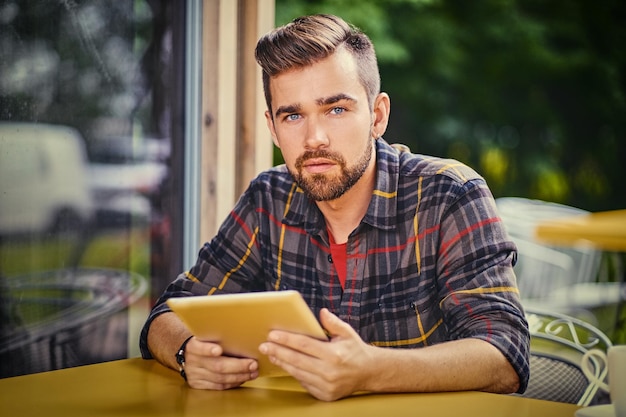 Guapo hombre hipster barbudo usando una computadora portátil en un café.