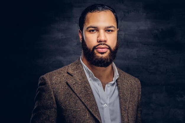 Guapo hombre de negocios afroamericano barbudo en una chaqueta clásica marrón. Aislado en un fondo oscuro.