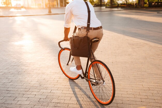 Guapo joven africano temprano en la mañana con bicicleta