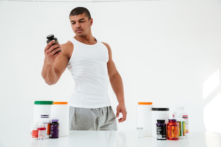 Foto gratuito guapo joven deportista junto a la mesa con nutrición deportiva
