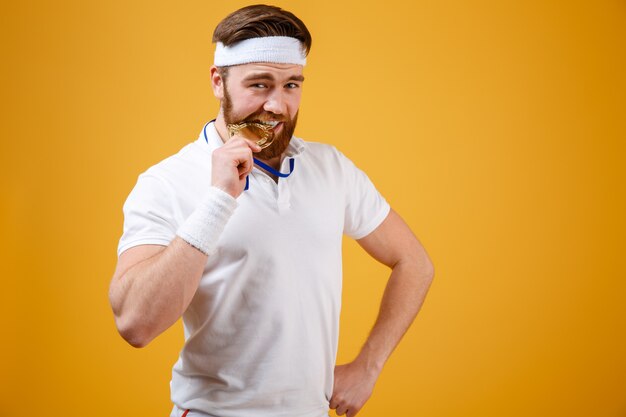 Guapo joven deportista con medalla de pie aislado