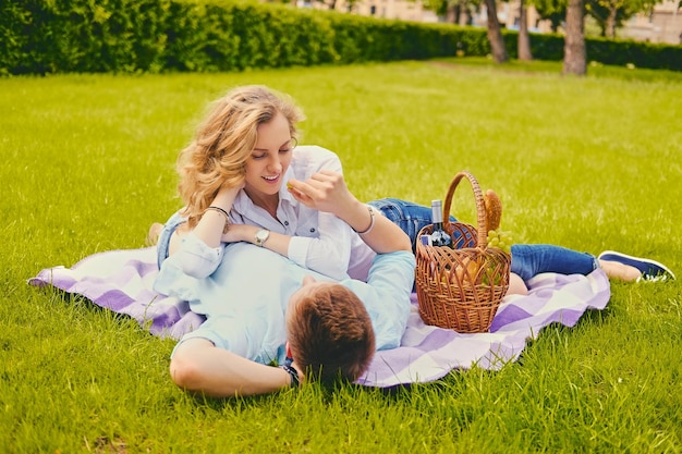 Guapo joven macho y hembra rubia en un picnic en un parque de verano.