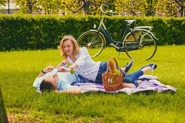 Guapo joven macho y hembra rubia en un picnic en un parque de verano.