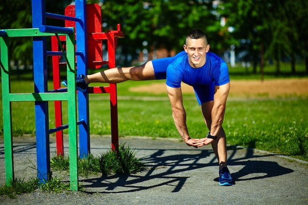 Guapo sano feliz atleta srtong hombre masculino haciendo ejercicio en el parque de la ciudad - conceptos de fitness en un hermoso día de verano en la barra horizontal