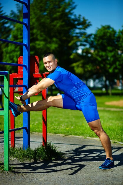 Guapo sano feliz atleta srtong hombre masculino haciendo ejercicio en el parque de la ciudad - conceptos de fitness en un hermoso día de verano en la barra horizontal