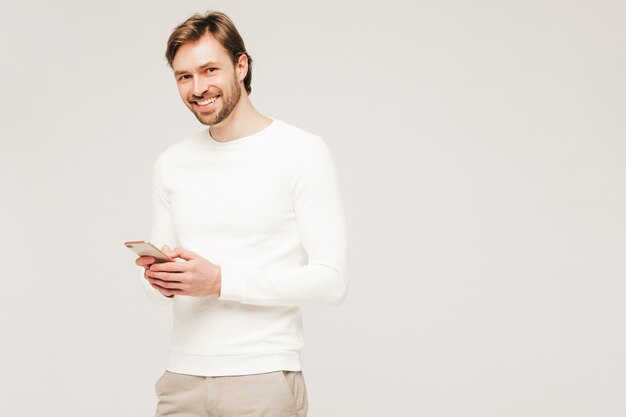 Guapo sonriente hipster lumbersexual modelo de hombre de negocios vistiendo pantalones y suéter blanco casual