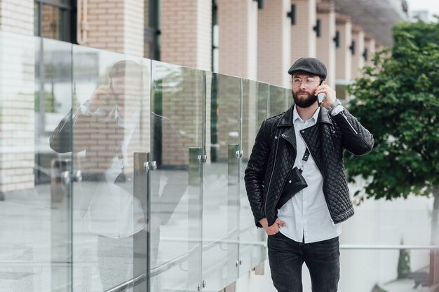 Guapo trabajador feliz hablando por teléfono, tomando café y va a trabajar por la mañana en una oficina moderna