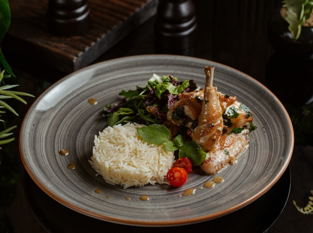 Foto gratuita guarnición de arroz con muslo de pollo a la parrilla picante en un plato de granito