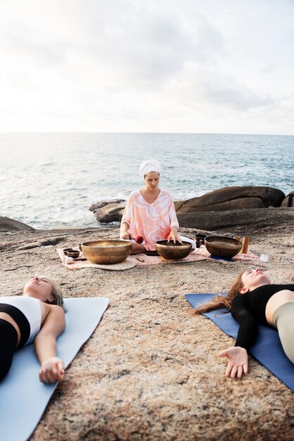Guía de meditación senior con cuencos cantores en la playa