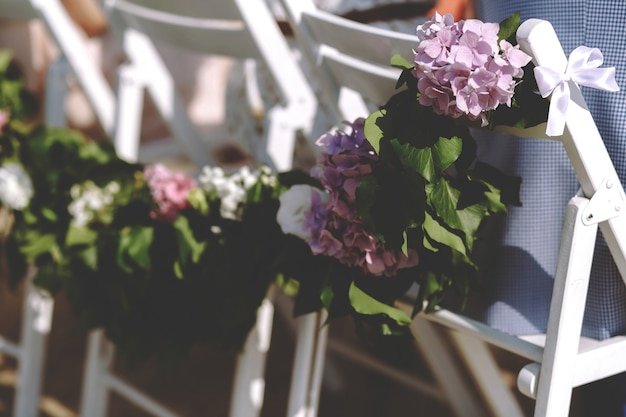 Guirnalda de hojas y hortensias moradas en las sillas.