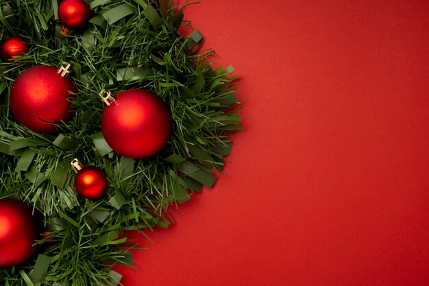 Guirnalda de Navidad hecha de hojas y bolas sobre una mesa roja