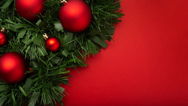 Guirnalda de Navidad hecha de hojas y bolas sobre una mesa roja