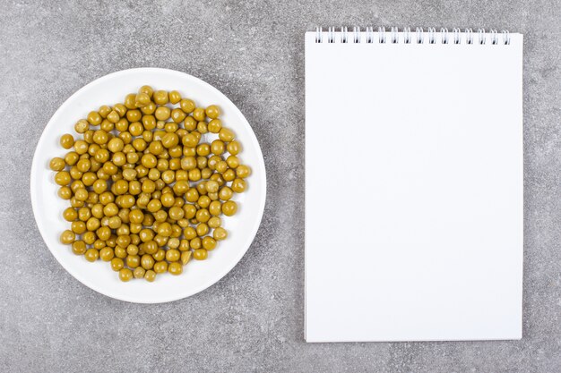 Guisantes enlatados en plato blanco con cuaderno