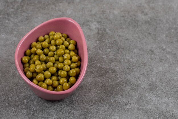 Guisantes vegetales enlatados en un tazón rosa.