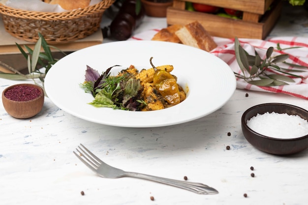 Guiso de verduras con carne, trozos de maíz, ají y vegetales, basílicos, perejil en plato blanco.