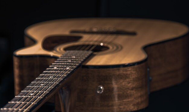 Guitarra acústica con una hermosa madera sobre un fondo negro de cerca.