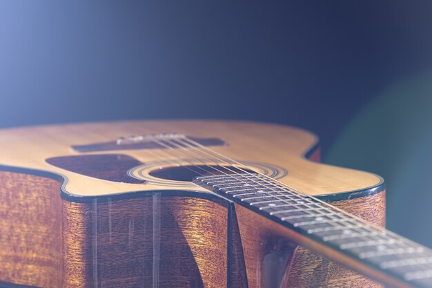 Guitarra acústica con una hermosa madera sobre un fondo negro a la luz de un foco.