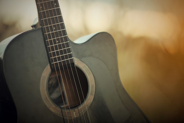 Guitarra acústica en un prado en el fondo del paisaje del atardecer