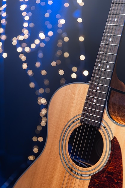 Foto gratuita guitarra acústica de primer plano sobre un fondo oscuro con luces bokeh