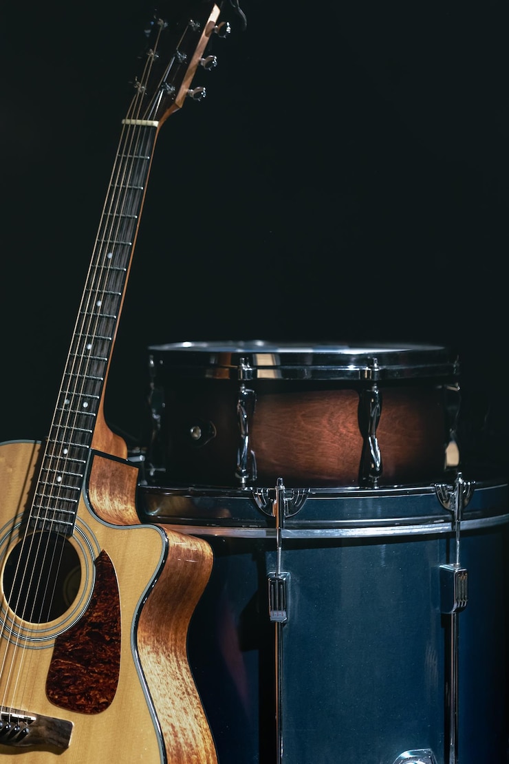 Foto gratuito guitarra acústica y tambor en un fondo negro aislado