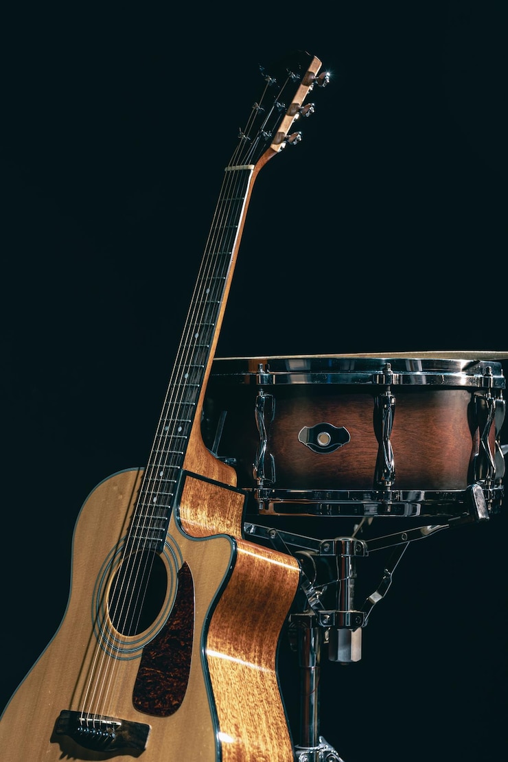Foto gratuito guitarra acústica y tambor en un fondo negro aislado