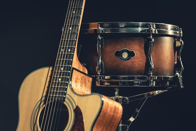 Foto gratuita guitarra acústica y tambor sobre un fondo negro aislado