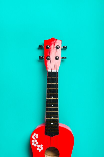 Guitarra clásica acústica roja sobre fondo turquesa