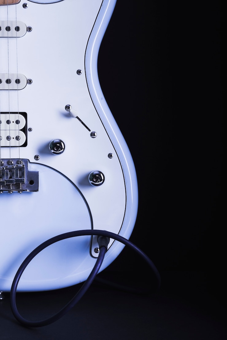 Foto gratuito guitarra eléctrica blanca sobre fondo oscuro