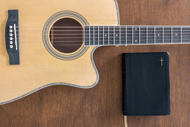 Guitarra y libro de la biblia en la vista superior de fondo de madera