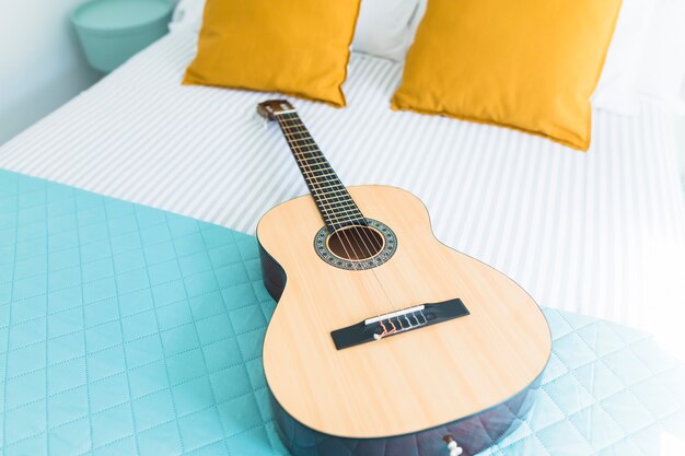 Guitarra de madera en la cama en el dormitorio