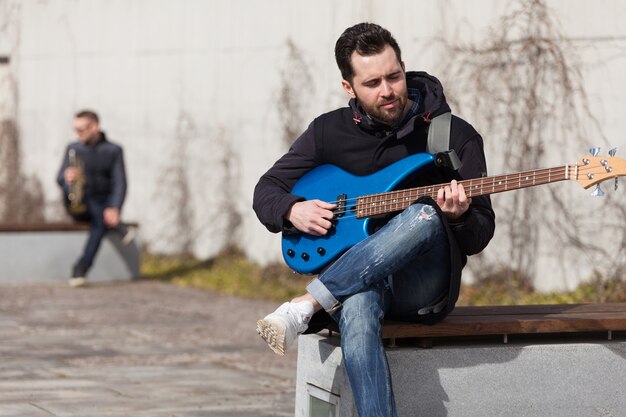 Guitarrista sentado en un banco