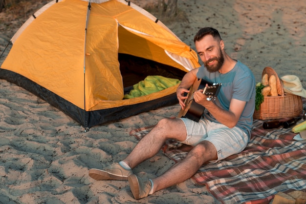 Foto gratuita guitarrista sentado junto a la tienda