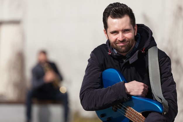 Foto gratuita guitarrista sonriente sujetando su guitarra