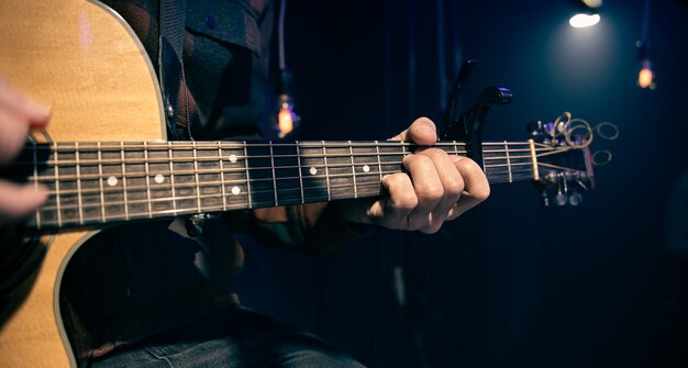 El guitarrista toca la guitarra acústica con capo