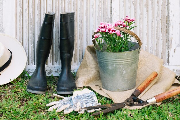 Gumboots con flores y herramientas en jardín.