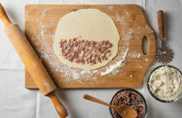 Gutab de carne cruda sobre tabla de madera. Cocina nacional azerbaiyana.