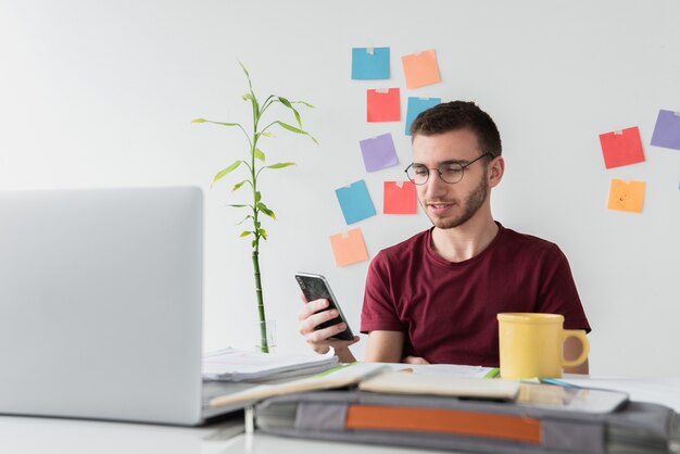 Guy en un escritorio de oficina mirando su teléfono