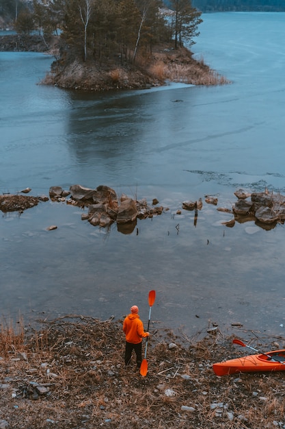 Guy está de pie en el lago congelado con un remo