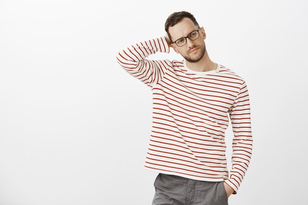 Guy piensa cómo invitar al hombre del trabajo a beber cerveza después del trabajo. Retrato de hombre guapo cansado con problemas en gafas negras, mirando a un lado