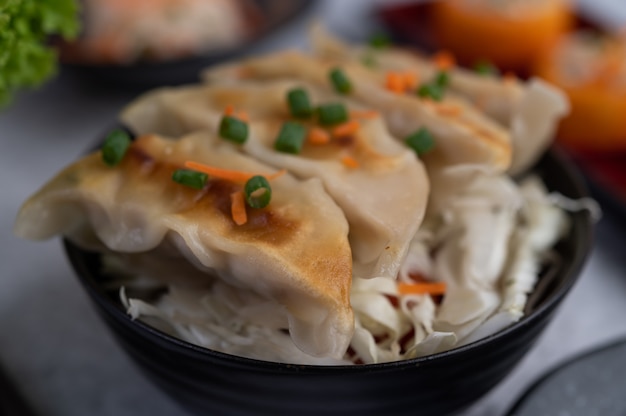 Gyoza en una taza negra con sushi.