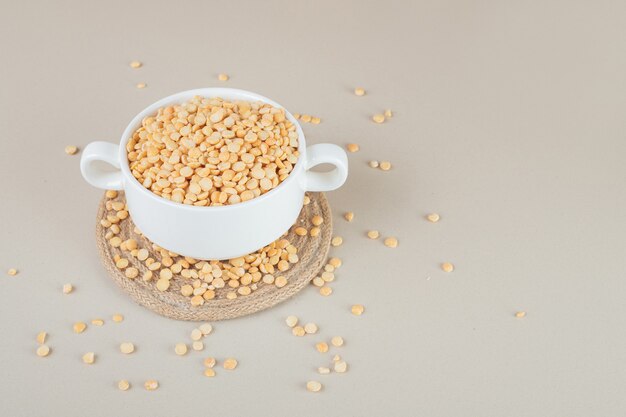 Habas de guisante amarillo en una taza de cerámica sobre hormigón.