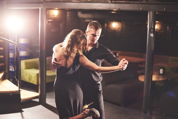 Hábiles bailarines actuando en una habitación oscura bajo la luz.