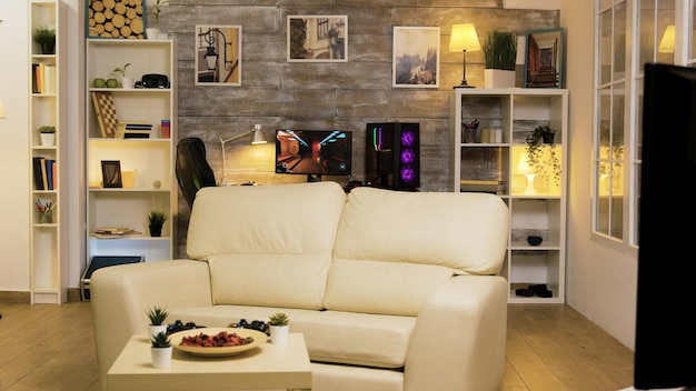 Habitación vacía con sofá en el medio y computadora de juego en el fondo.