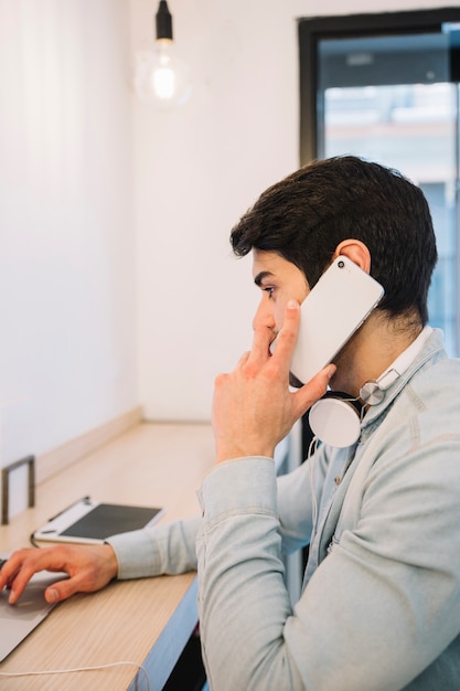 Hablando por teléfono hombre trabajando en la computadora portátil