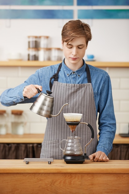 Hacer café pouron. Buen barista preparando una bebida de café, con aspecto concentrado.