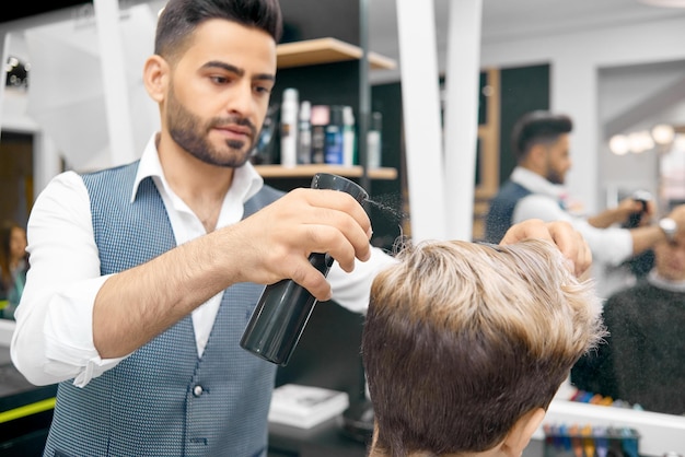 Foto gratuita hacer un nuevo peinado para un modelo masculino usando laca para el cabello