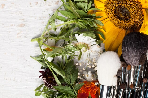 Hacer pinceles sobre un montón de flores silvestres sobre fondo de madera