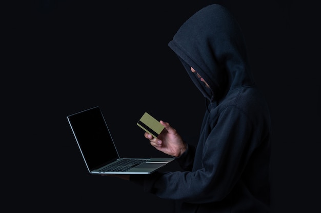 Hacker con una computadora portátil y una tarjeta de crédito dorada