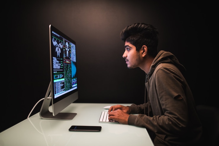 Foto gratuito hacker indio usando computadoras para robar datos en el escritorio oscuro
